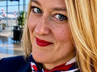 FltAttendantAbby smiles while looking at the camera, showing her blonde hair and red lipstick in a close-up shot.