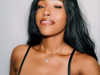 FoxyHaven poses with long dark hair, wearing a black strap top against a plain light background.