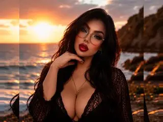 Glamorous woman in a black lace outfit posing during a golden sunset on a rocky beach.