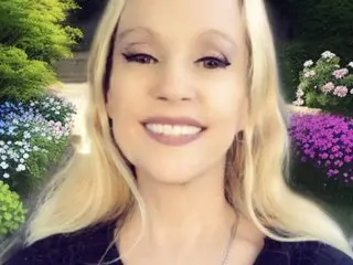 Gartersex smiles while looking at the camera, showing her blonde hair and light skin in a close-up headshot.