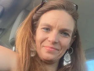 GeminiLoveXO has long brown hair and a direct gaze, posing close-up in a car setting.