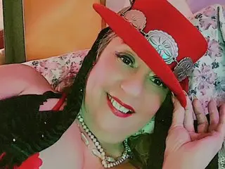 Smiling woman in red western hat and silver jewelry relaxing on a floral patterned pillow.