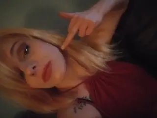 GirlGoneWireless poses with her blonde hair down, wearing a red top and looking directly at the camera.
