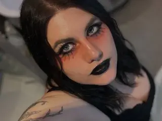 GothSuccubusBabe poses with long black hair and dark makeup, showing her bare shoulders and chest in a close-up shot.