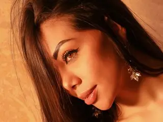 Grace_Jonees poses with a close-up headshot, showing her long dark hair and eyes while looking toward the camera against a warm background.