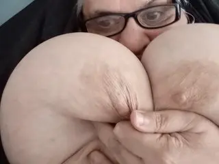 GrannyHugeBoobs looks into the camera while squeezing her massive, heavy breasts with both hands.