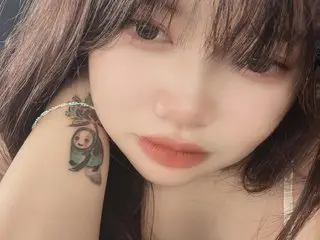 HaniSexxi poses close-up, showing her face, dark hair, and a small tattoo on her shoulder.