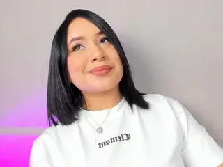 HannaKarson wearing a white t-shirt with black text, looking off-camera with her black hair styled in a blunt bob.
