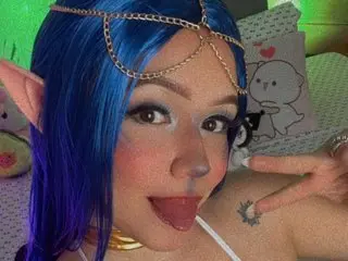 HannaKimura wearing a blue wig and gold chain headpiece, posing with a playful expression.