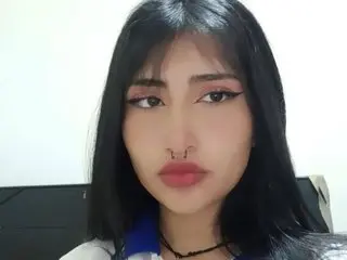 HannaLiss18 with long black hair and winged eyeliner, wearing a blue and white top and a black choker, looking directly at the camera.