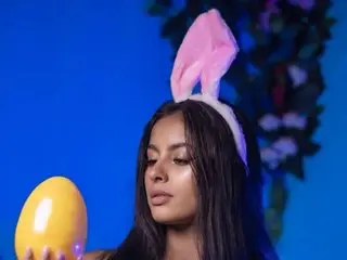 Hannysun poses with a pink bunny ear headband and long dark hair against a blue background.