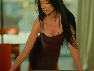 Haylie_Milf — Elegant woman in a dark brown slip dress posing in a modern, sunlit room.