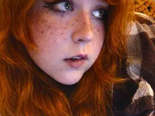 HazelEyedGinger shows off her red hair and freckled face in a close-up headshot looking directly at the camera.