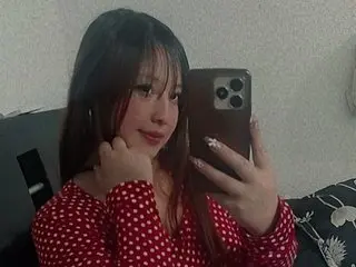 HeilySamanta poses for a mirror selfie, showing her long dark hair and red polka-dot top while looking at the camera.