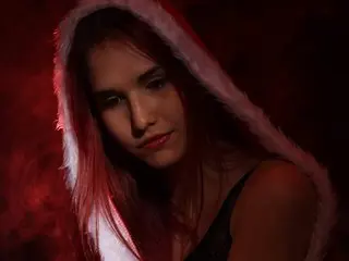 HeraLuna poses with her long hair down, wearing a white fuzzy headpiece or trim against a dark, moody background.