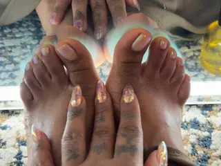 HippieSpiceFeet shows off her bare feet and toes, held up close to the camera against a soft, blurred background.