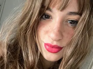 HoneyNina129 shows her face and long brown hair with bangs, looking directly at the camera in a close-up shot.