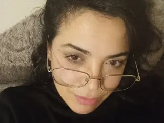 ITALIANAQUIPERTE wearing glasses and looking at the camera while lying down.