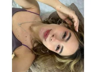Imross_bX — Imross_bX smiles while lying back, wearing a purple top with thin straps and her hair loose.