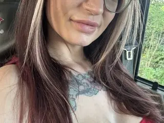 InkedJade shows off her long brown hair and neck tattoo while posing close-up in a red top.