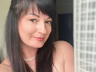 IraCherryNow smiles while looking at the camera, showing her long dark hair and bare shoulders in a close-up shot.
