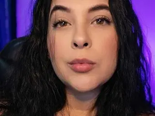 IsaCo looks directly at the camera with her long, dark wavy hair framing her face in a close-up shot.