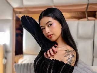 Isa_Moon poses with her long dark hair, wearing a black textured top that shows her shoulders and cleavage.