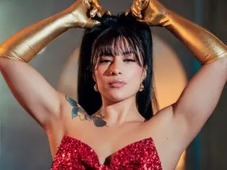 Isabellafit_V poses in a red sequin dress and long gold gloves, running her hands through her dark hair.