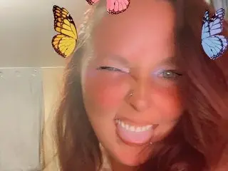 ItsKimber winks and sticks her tongue out at the camera with colorful butterfly filters on her hair.