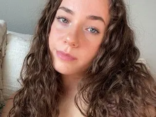 Itsstarxo shows off her long, wavy brown hair and bare shoulders in a close-up headshot shot against a plain white background.