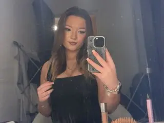 IvoryOfficial poses for a mirror selfie, wearing a black tank top and showing her long brown hair and light makeup.
