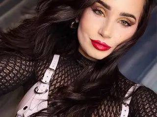 IvyAstor poses in a black mesh long-sleeve top and white lace bra, showing her dark wavy hair and red lipstick.