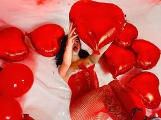 Excited woman in a red lace outfit lying amidst red heart-shaped balloons for a romantic Valentine's Day mood.