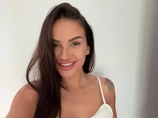 Ivytempt smiles with her long dark hair down, wearing a white lace camisole against a plain white background.