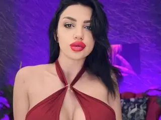 Beautiful woman in a red halter dress posing against a vibrant purple background with a glamorous mood.