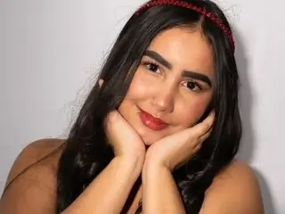 Smiling young woman with long dark hair and red headband posing against a white background.