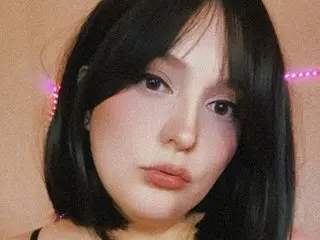 JadeViolet poses close-up with her long black hair framing her face and a soft glow behind her.