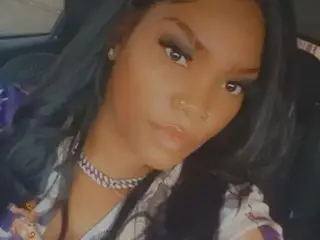 JamieRoseBlack poses with long dark hair, looking directly at the camera with a soft expression in a close-up shot.