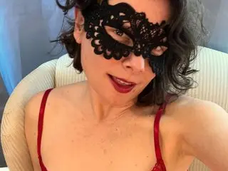 Jane_Honeybee wears a black lace mask and red bra, posing with her dark hair down in a bright setting.