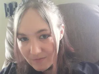JassieJak looks directly into the camera with a neutral expression, showing her face and long, light-brown hair.