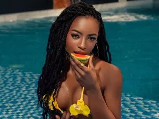 JaylahG poses in a blue tiled pool wearing a yellow bikini, running her hand over her chest while looking at the camera.