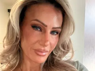 JennaAlexanderXXX poses with a close-up headshot, showing her long blonde hair and light makeup against a plain background.
