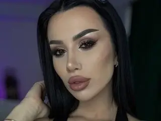 Woman with glamorous smoky eye makeup and long dark hair posing for a moody close-up portrait.