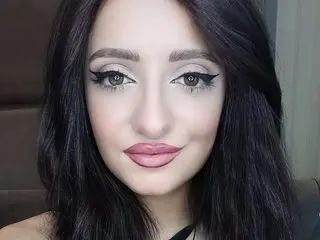 Young woman with long dark hair and glamorous winged eyeliner makeup looking at the camera.