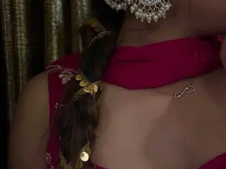 Juicy_candy68 wears a pink top and gold jewelry, posing with her dark hair tied back in a thick braid.