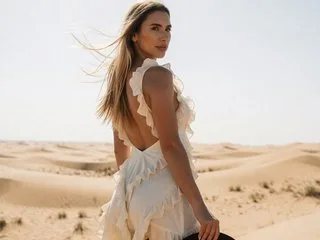 JullyBlair poses in a white ruffled dress looking over her shoulder in the desert dunes.