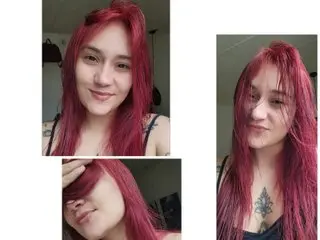 KAMY_STONE with long pink hair, looking at the camera in a close-up headshot against a plain background.