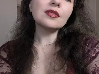 KARLEENx poses with long dark hair, wearing a dark red lace top that shows her cleavage and neck.