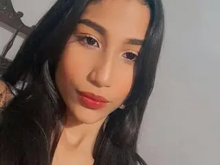 Kalifa_h poses with long dark hair and a direct gaze, showing her face and shoulders against a plain background.
