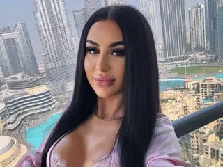 KathrynSin has long black hair and wears a low-cut pink top, posing close-up in a high-rise setting with city buildings behind her.